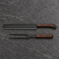 Black hammered brisket slicer and two-tine carving fork with wenge handles on dark stone