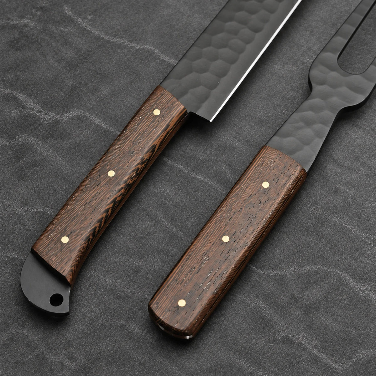 Close-up of wenge handles with brass pins on the black slicer and carving fork