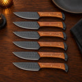 Set of 6 black hammered steak knives with rosewood handles on a dinner table