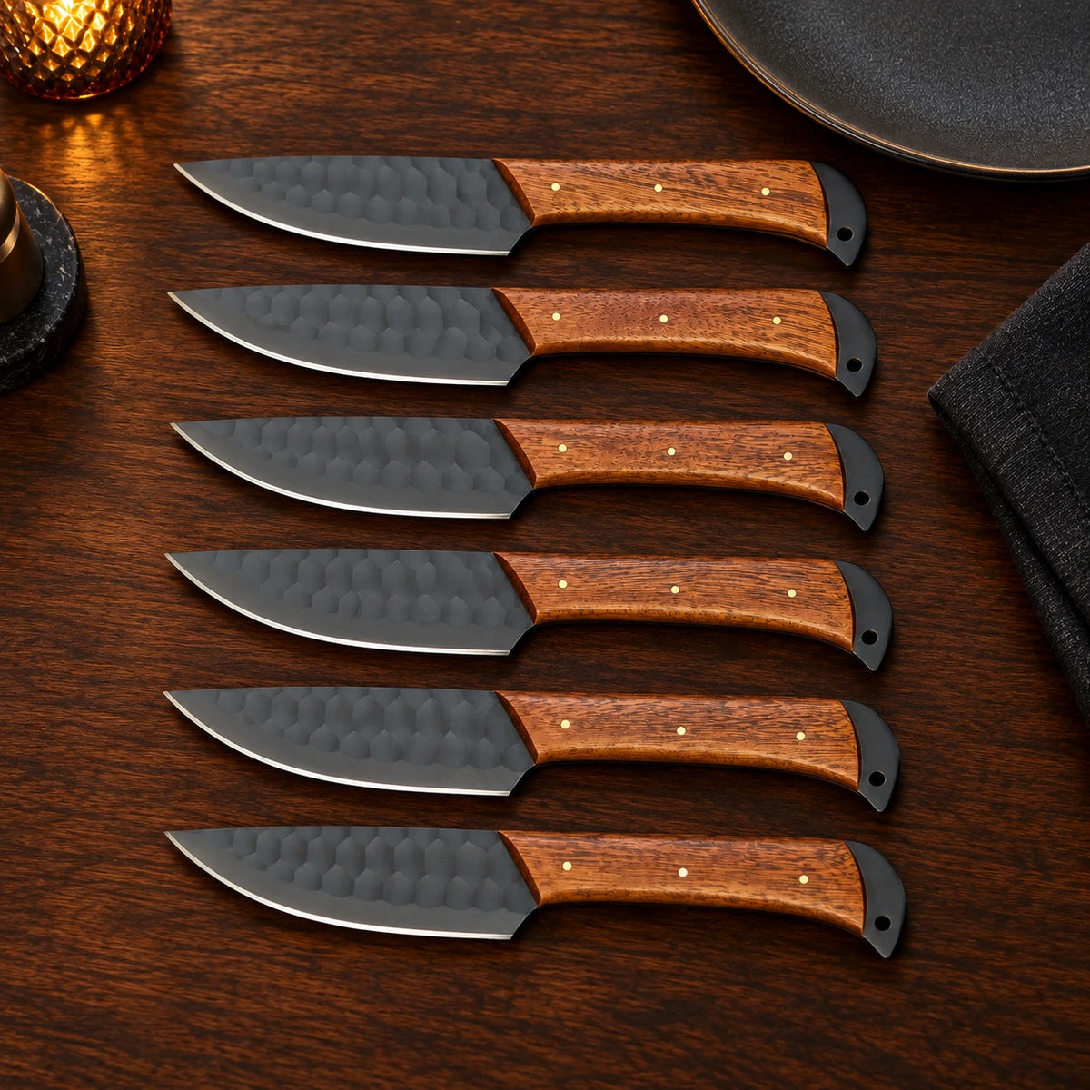 Set of 6 black hammered steak knives with rosewood handles on a dinner table