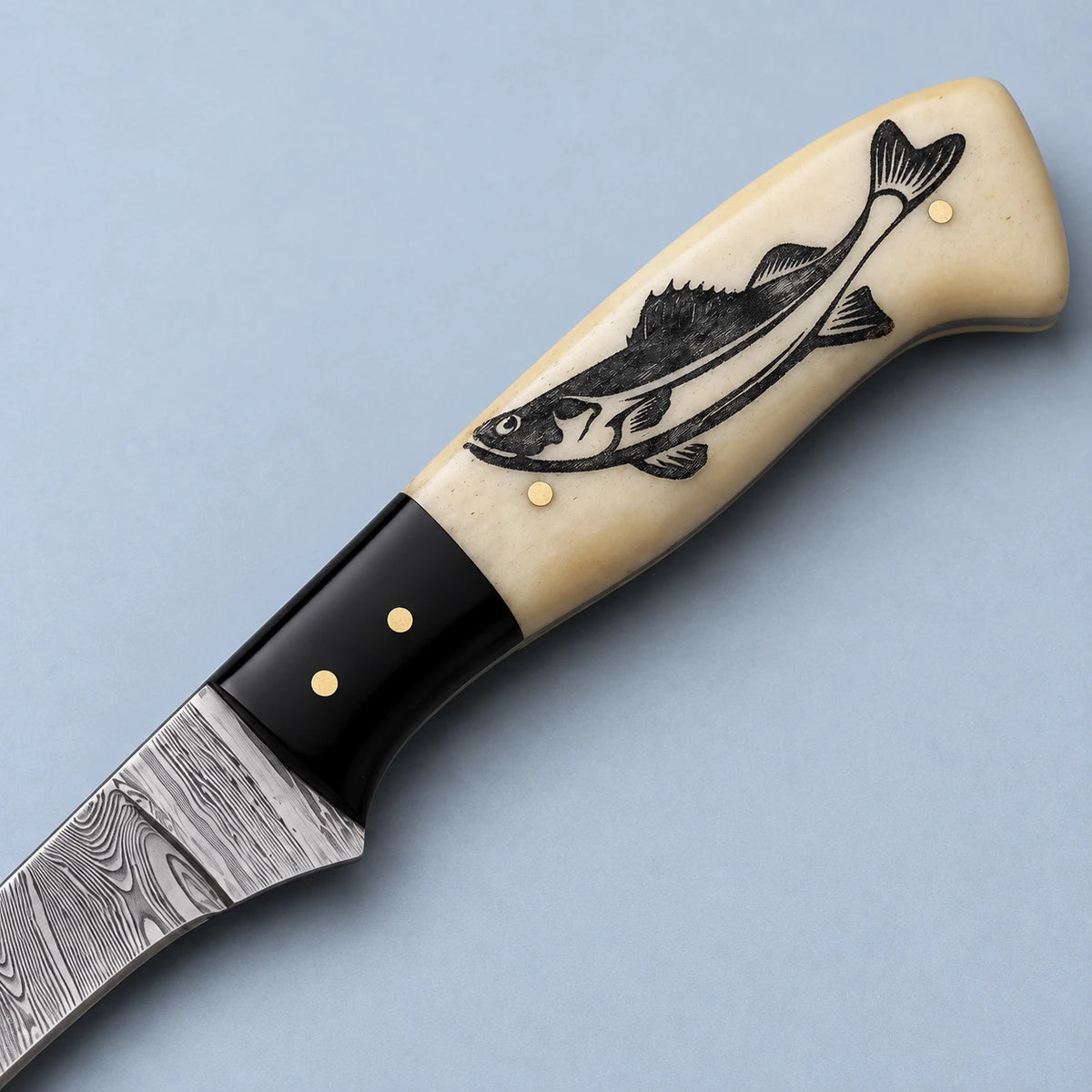 Close-up of engraved fish design on the camel bone handle with brass pins and horn bolster